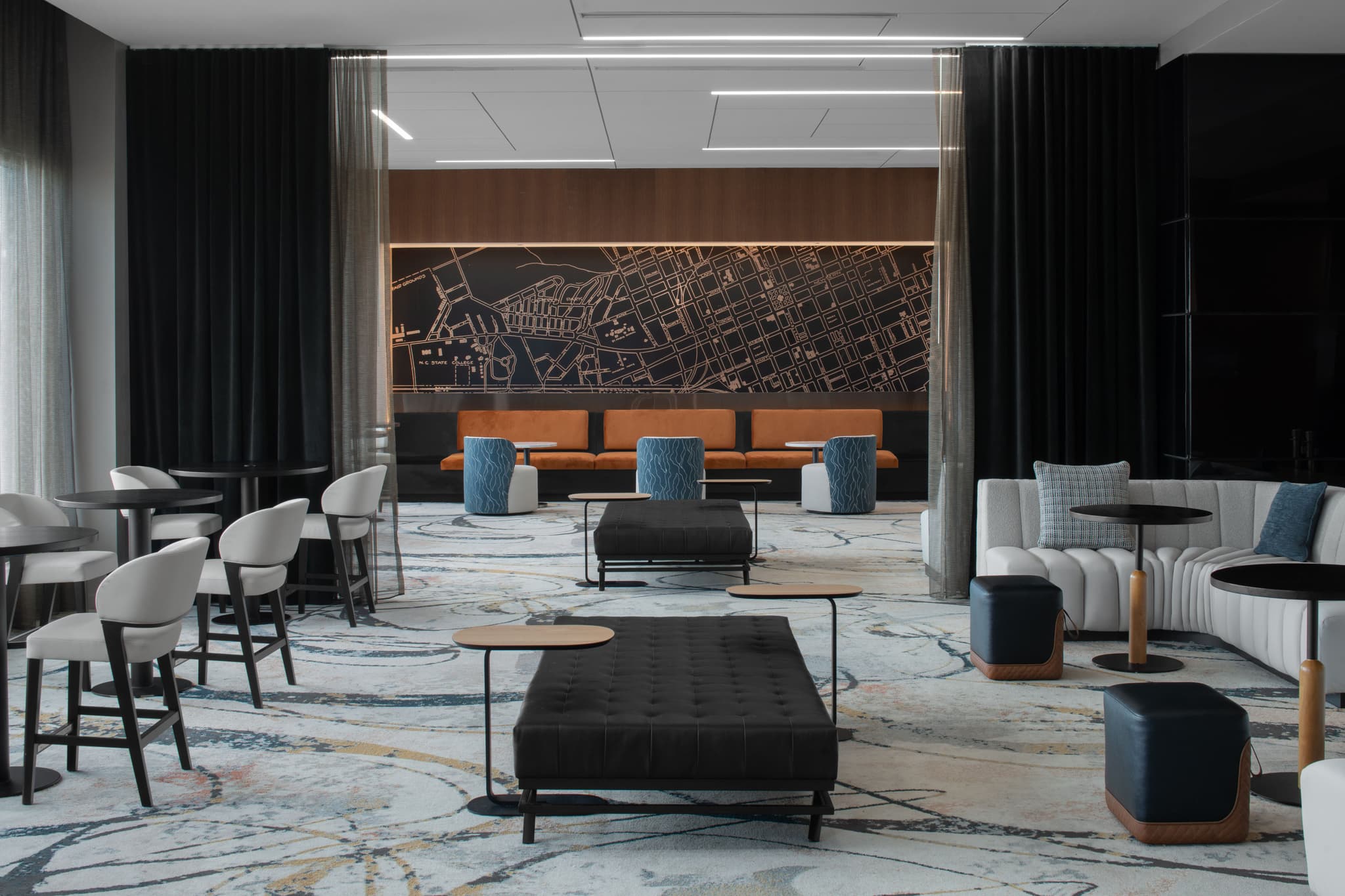 A stylish lounge area at AC Hotels Raleigh Level 7, with contemporary furniture, a city map mural, and an inviting ambiance