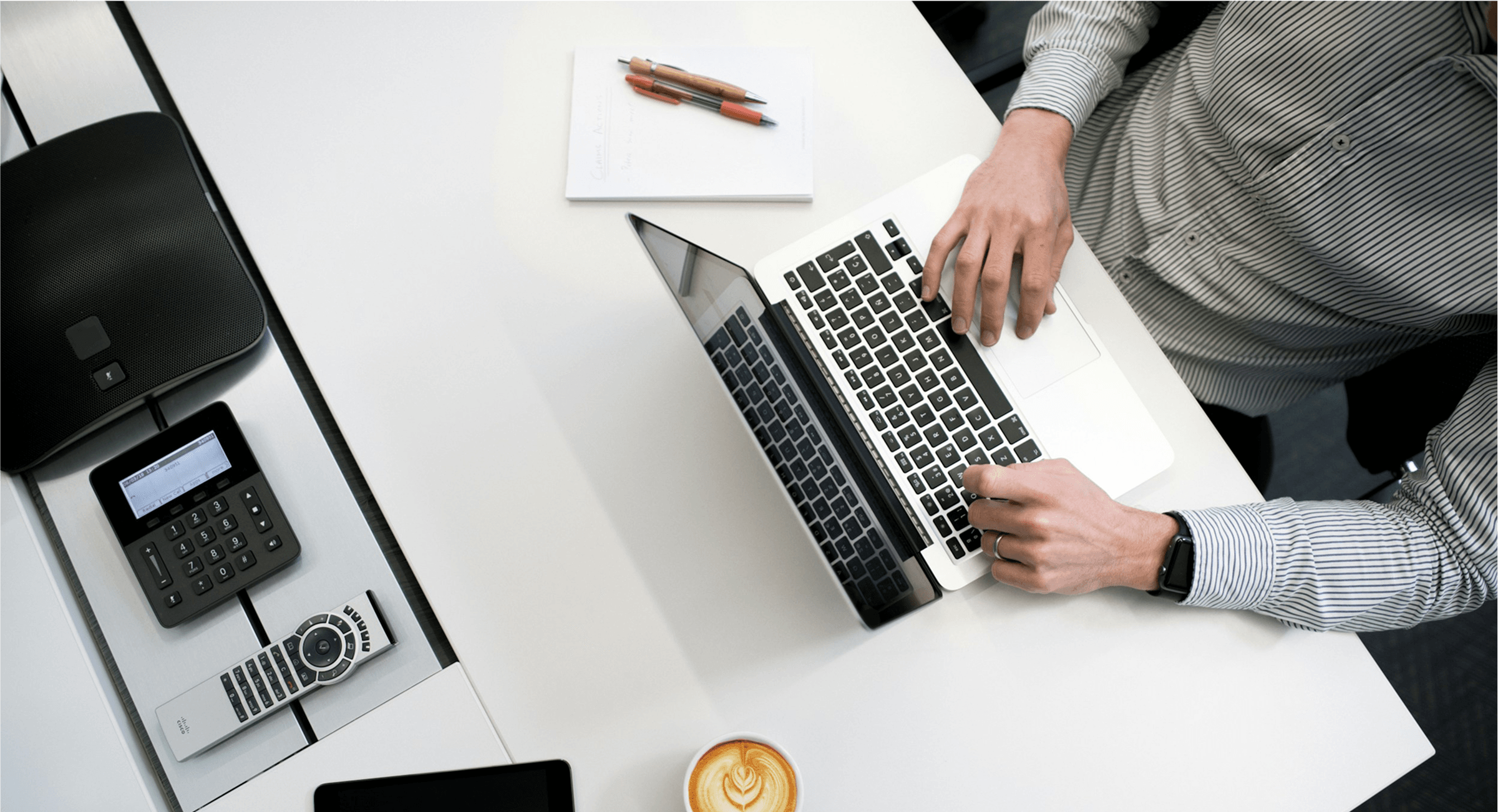 A professional workspace setup featuring a person typing on a laptop at a white desk